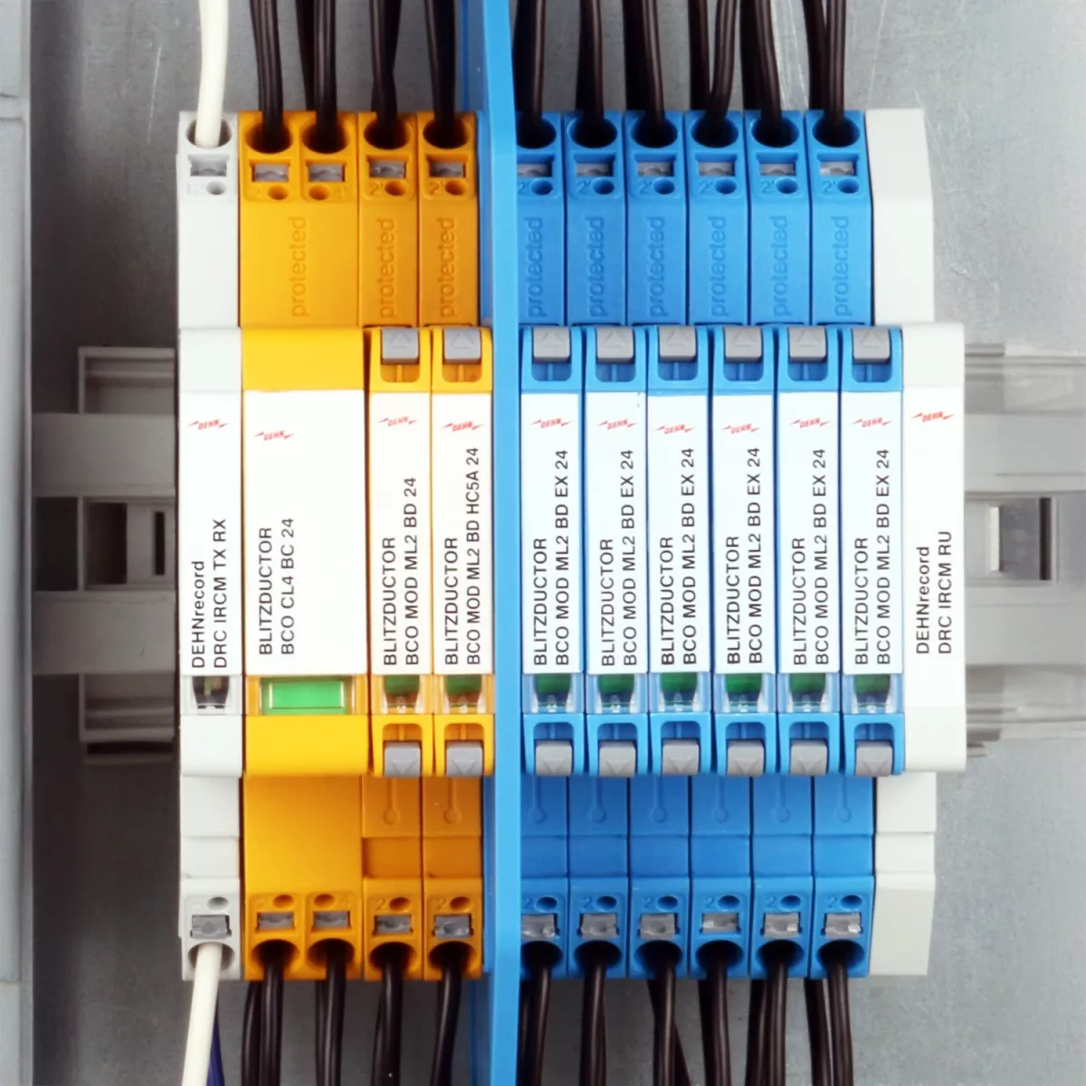 Scaricatori combinati gialli e blu montati su guida DIN e completamente cablati davanti a un quadro elettrico aperto.