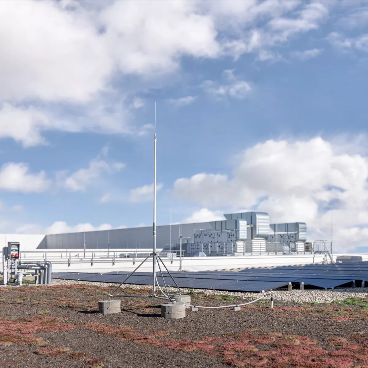 Edificio con un HVI light plus sul tetto piano. Sullo sfondo è visibile un impianto fotovoltaico.